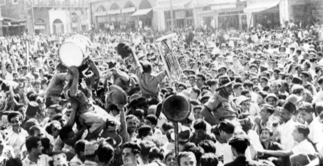Crowds of people, soldiers and civilians, celebrate in the street on VE Day (Victory Europe).
