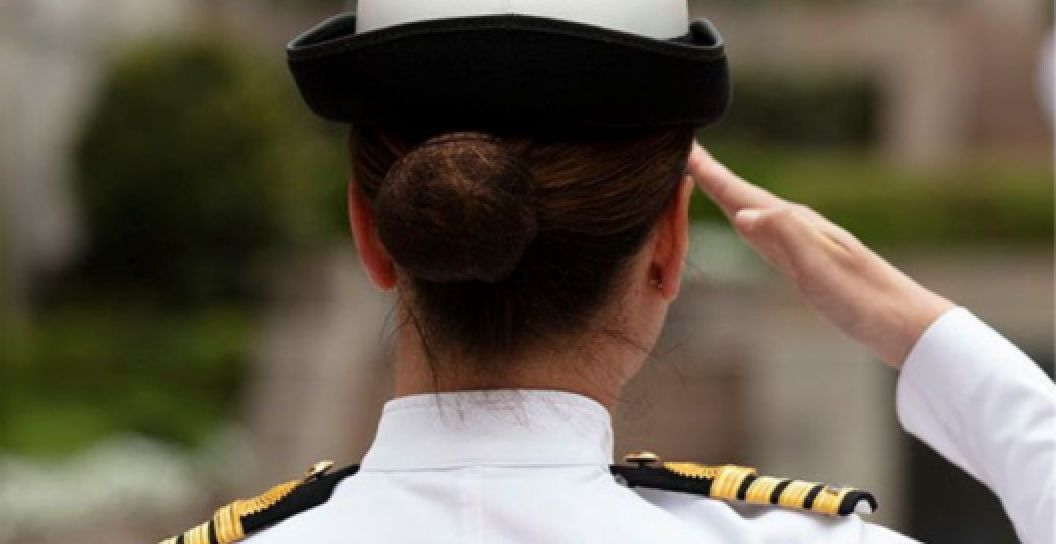 An image of a woman from behind saluting.