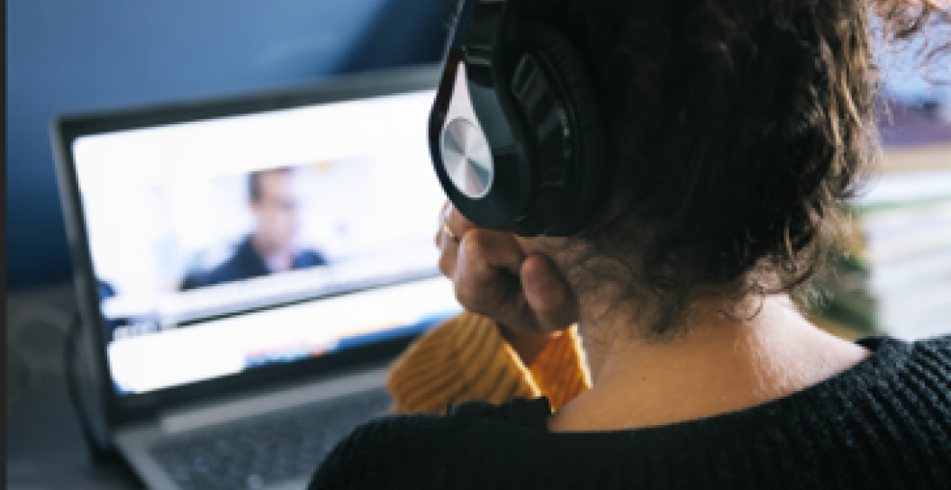 Adult wearing headphones watching computer screen
