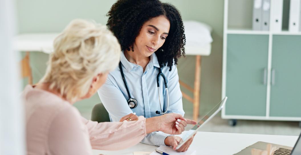 Female doctor conducting a consultation with a patient. Both are looking at a computer tablet