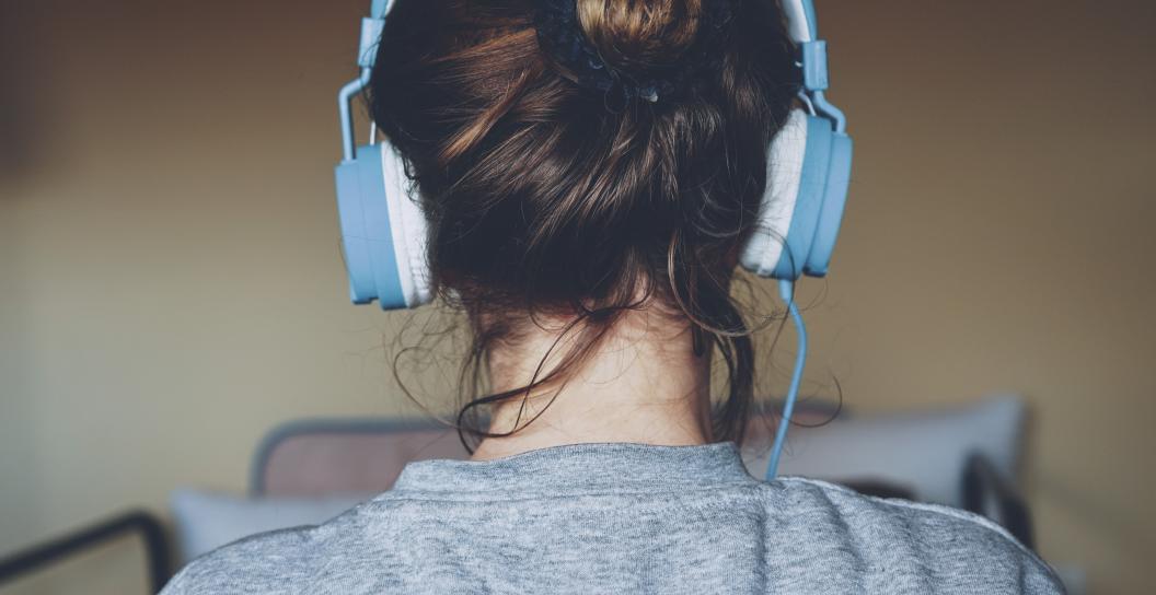 Woman wearing blue headphones from behind