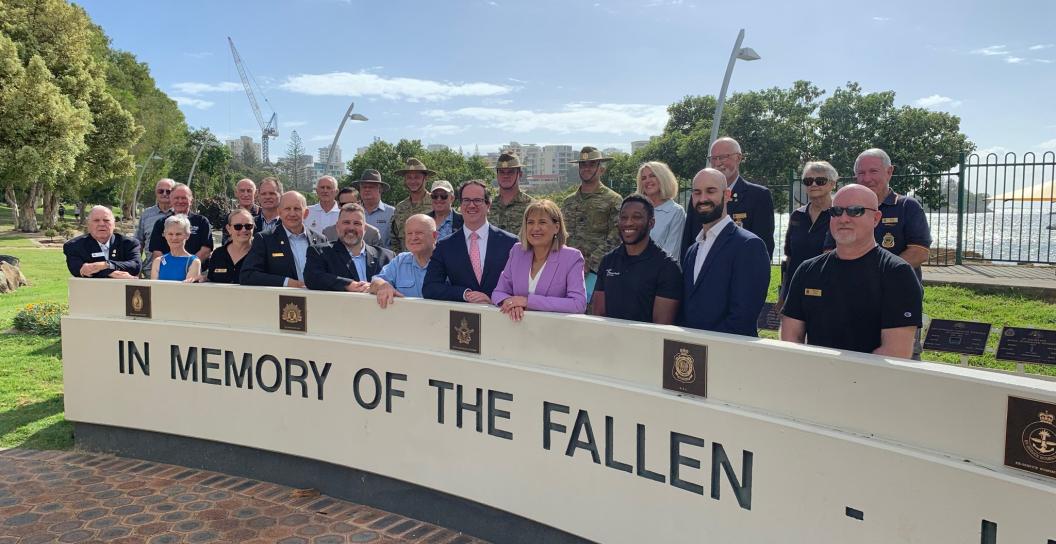 Veterans, RSL LifeCare members and the Minister for Veterans' Affairs in front of a memorial wall