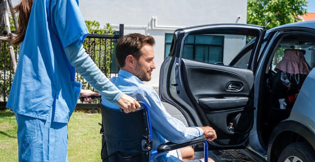 Carer helps man into car
